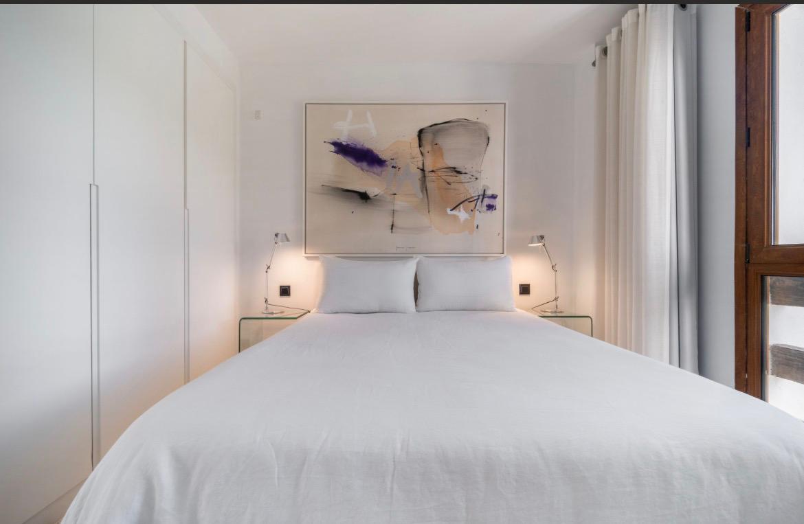 Serene white bedroom with abstract art above the bed