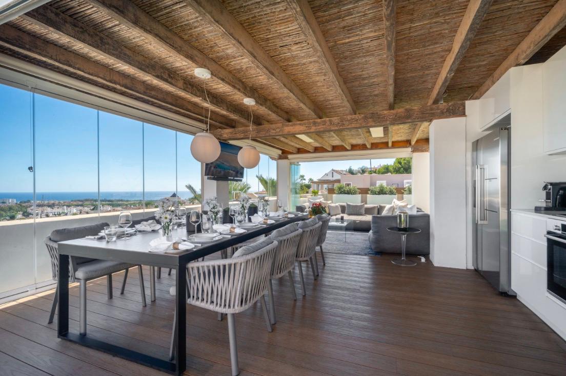 Covered terrace with wood-beam ceiling and long dining table facing the sea