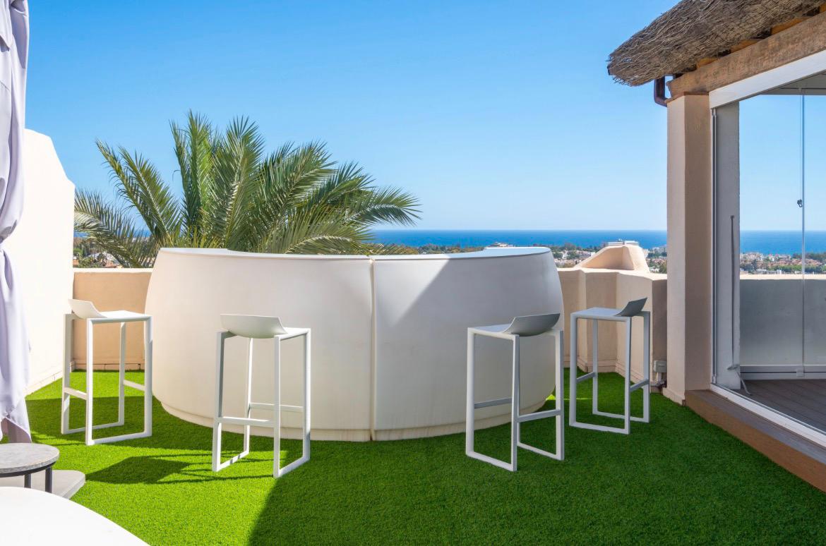 Rooftop bar with stools, palms and panoramic sea view